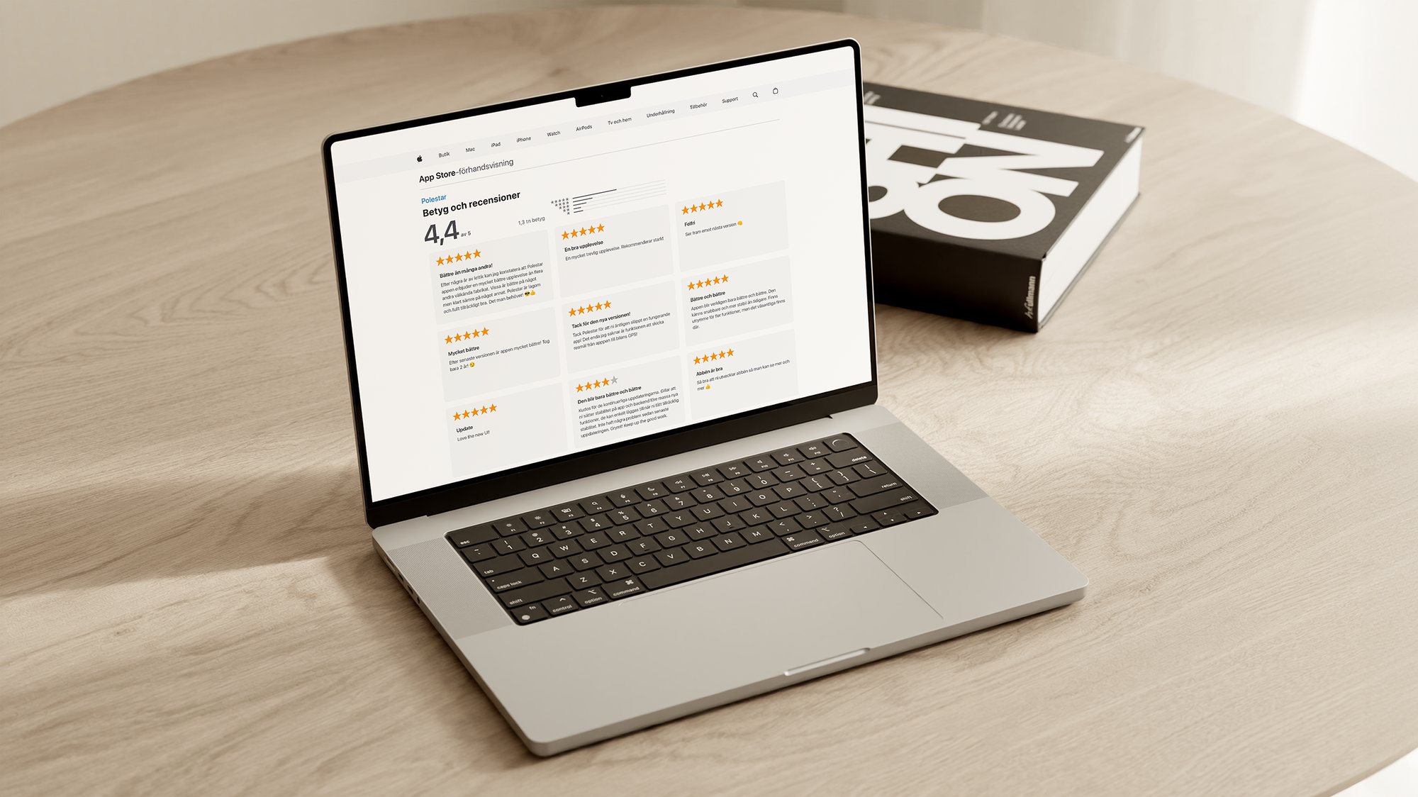 Laptop on a wooden table displays app store ratings in Swedish, averaging 4.4 stars. A book labeled 'ON' is nearby.