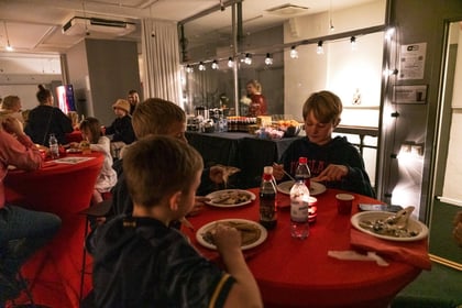 Children eating pancakes in a room with christmas decorations and cozy lighting.