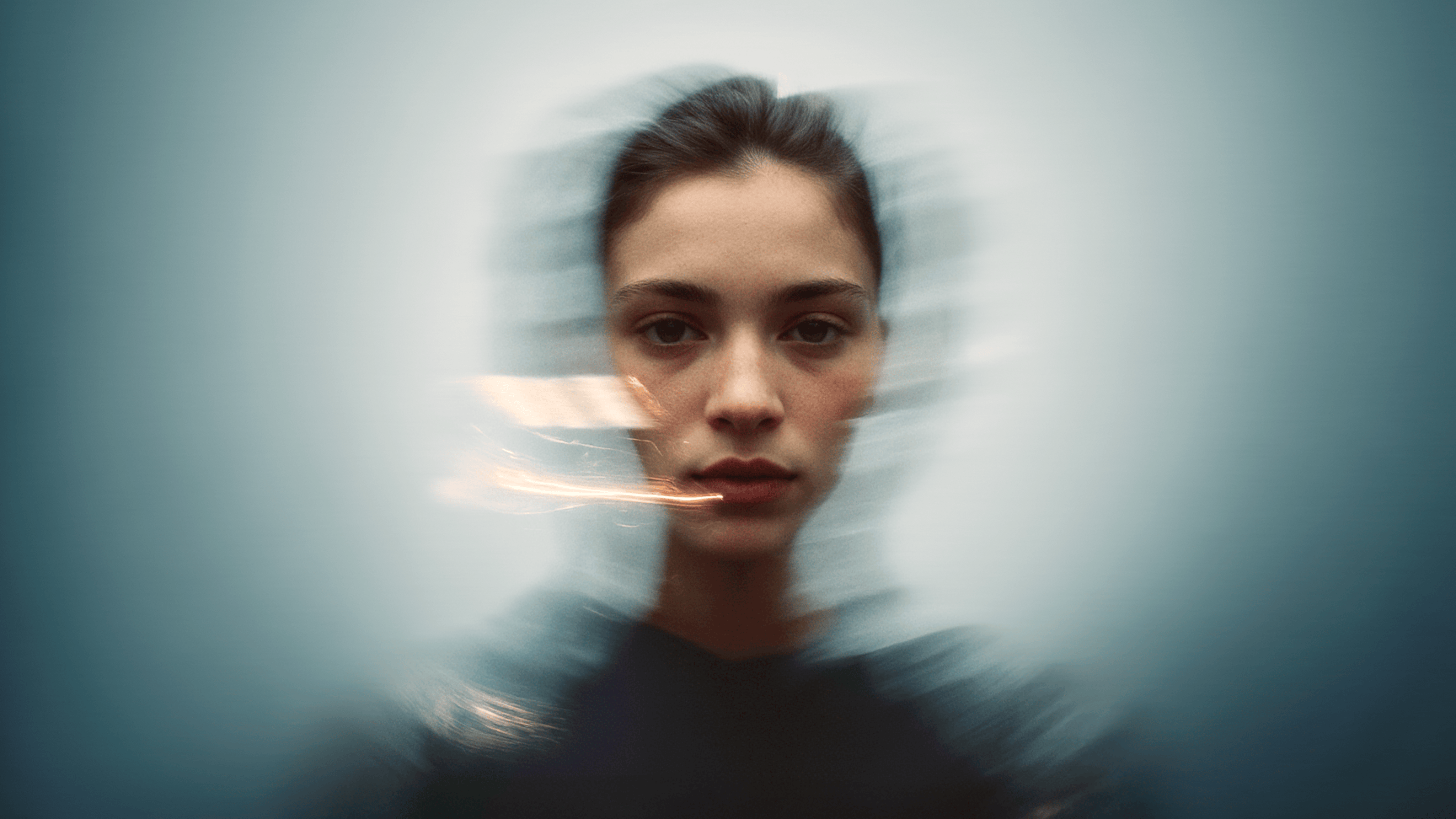 A woman's face in focus with a blurred, abstract motion effect surrounding her, creating a sense of movement and depth.