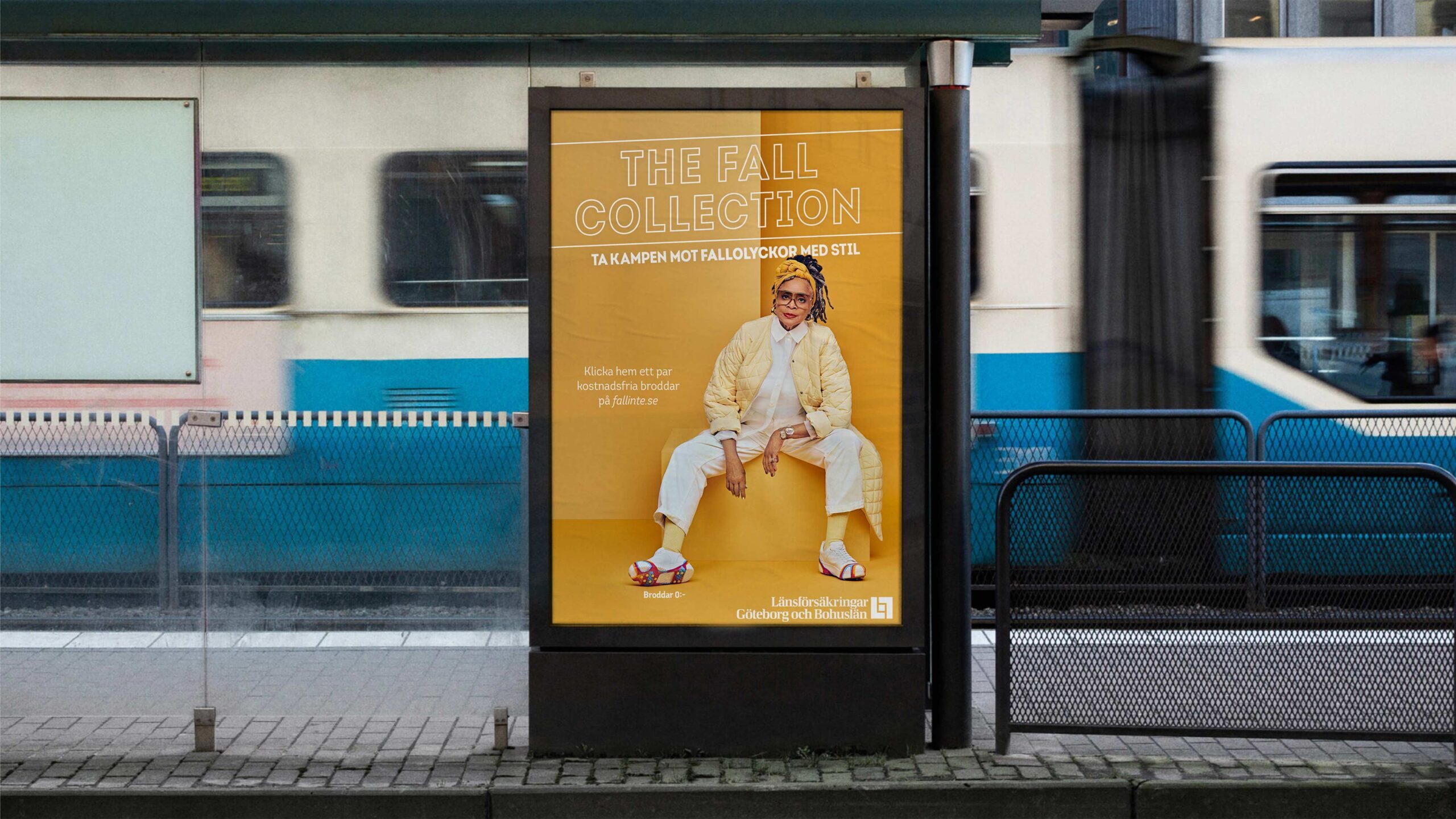 Public transportation stop with an ad for 'The Fall Collection' in yellow, featuring a person in stylish autumn clothing.