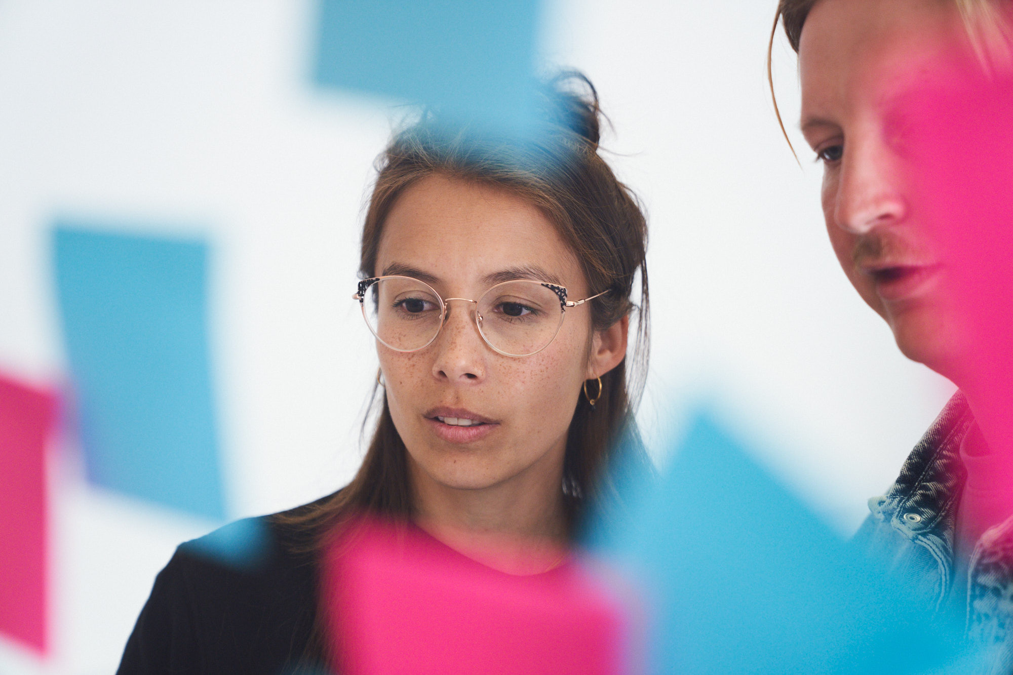 Colorful sticky notes in pink and blue floating in the foreground against a blurred background.