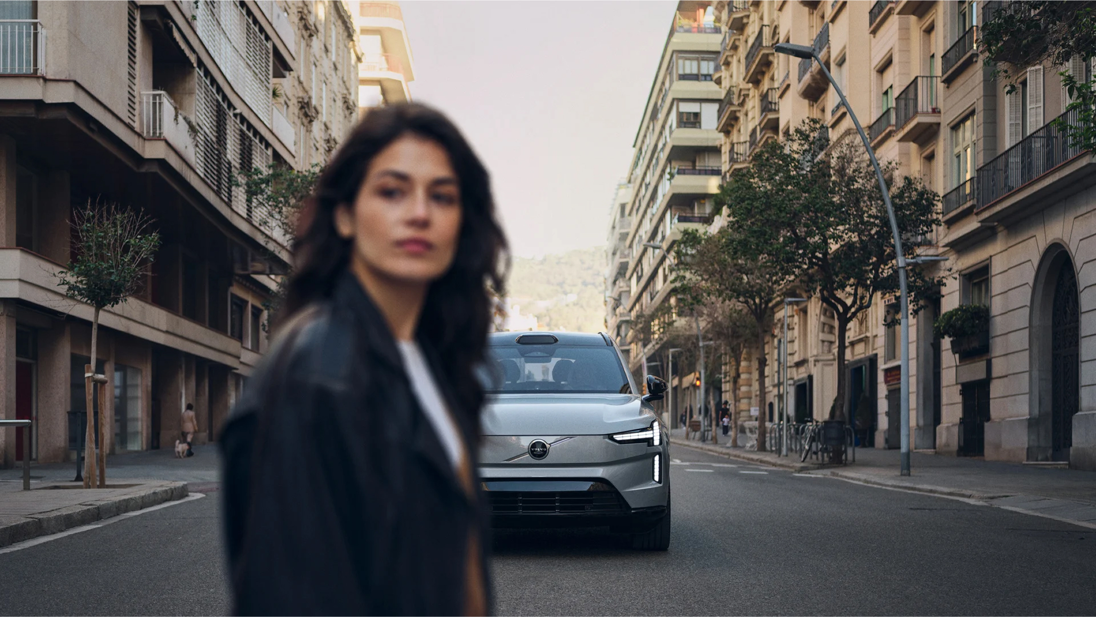 Woman walking on city street with electric car in background