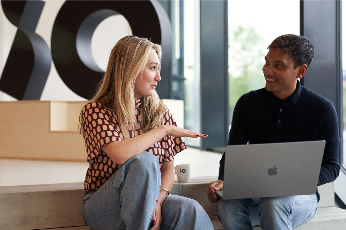 Two colleagues discussing at iO office with laptop